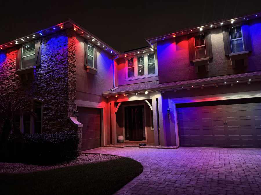Permanent lighting in red and blue on Florida stone home at night